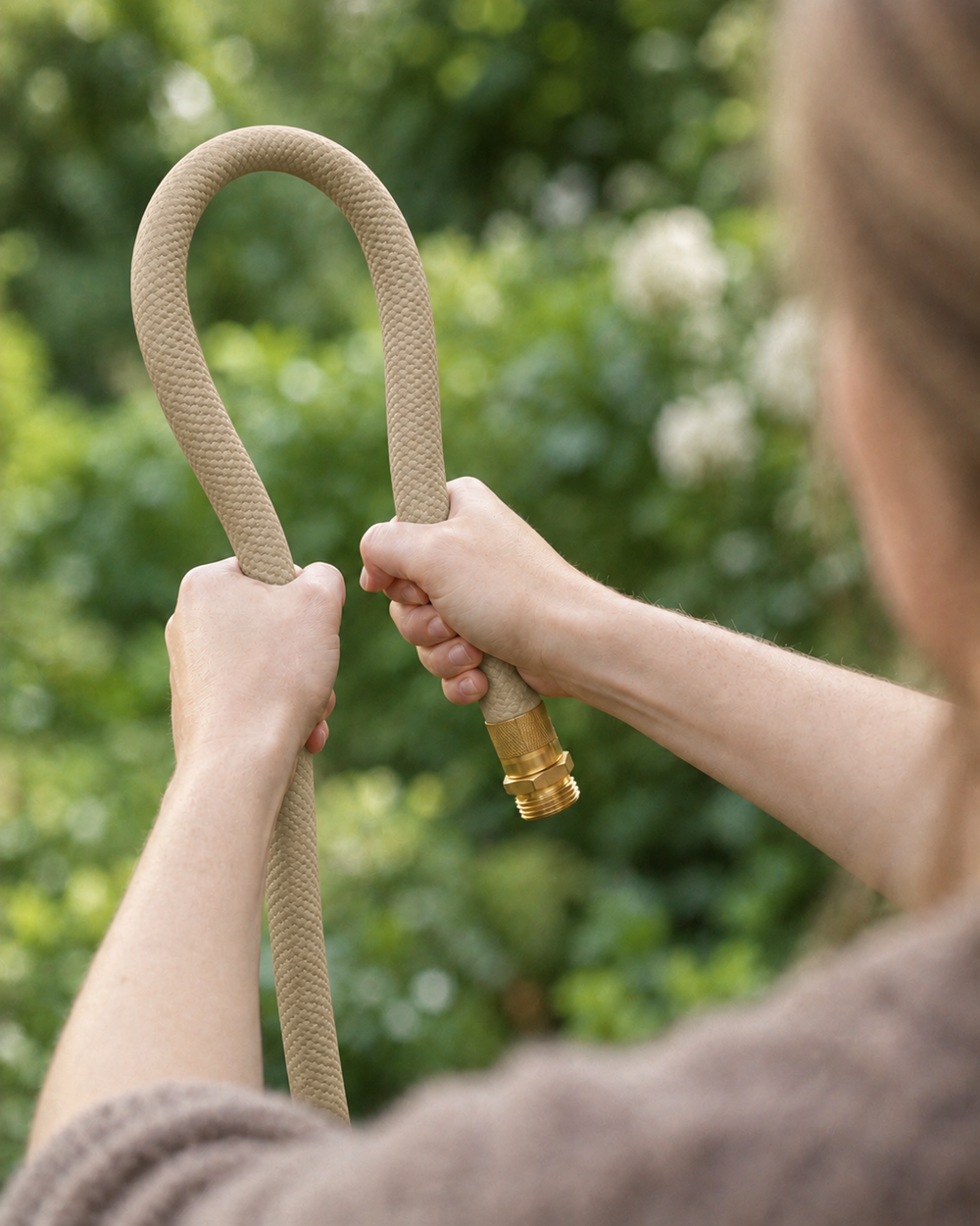 Flexible sand beige garden hose bent by hand outdoors