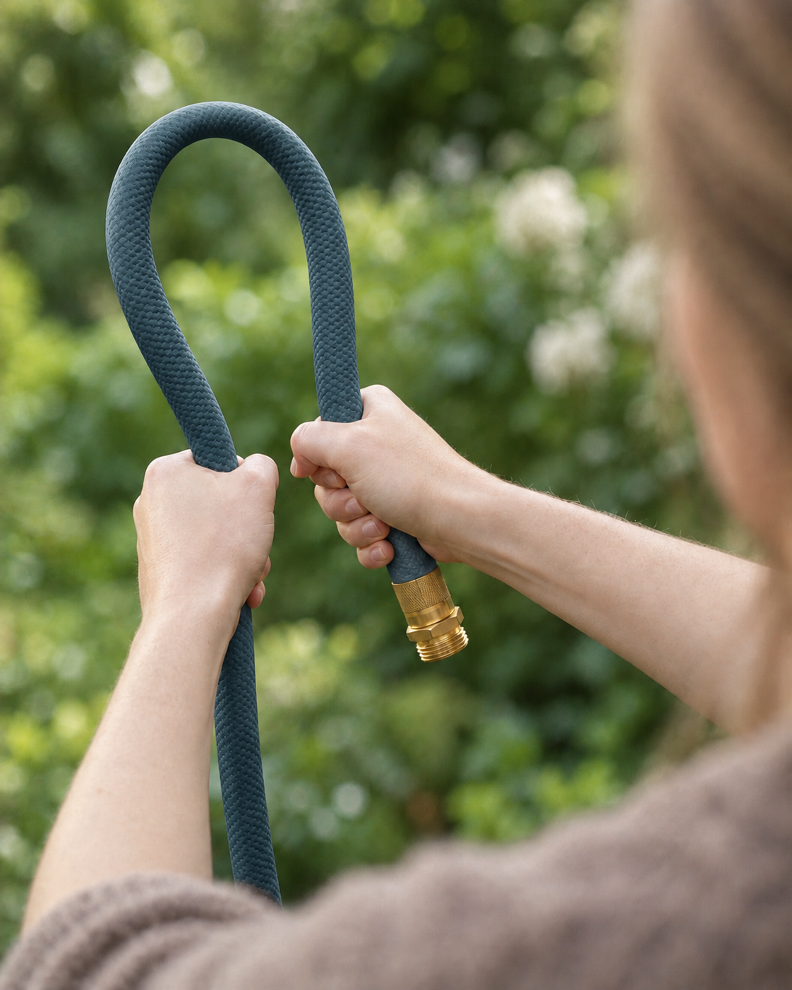 Flexible slate blue garden hose bent by hand outdoors