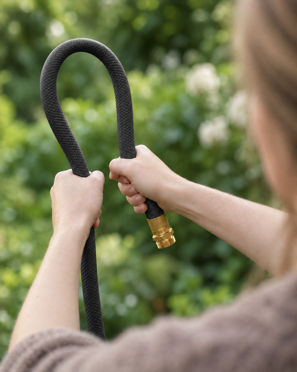 Flexible charcoal black garden hose bent by hand outdoors