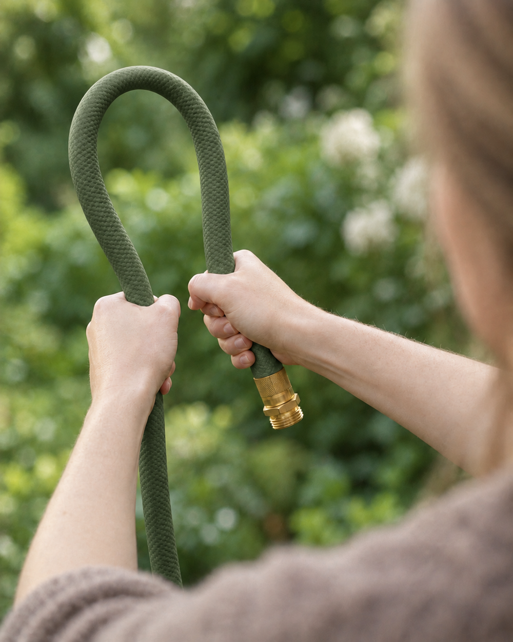 Flexible olive green garden hose bent by hand outdoors