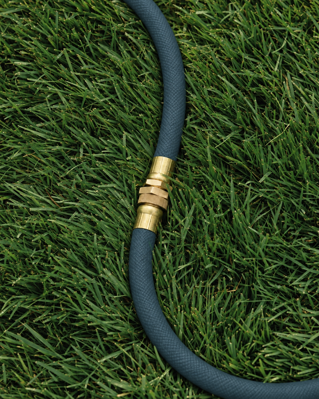 Slate blue garden hose with brass fittings coiled on a wooden patio